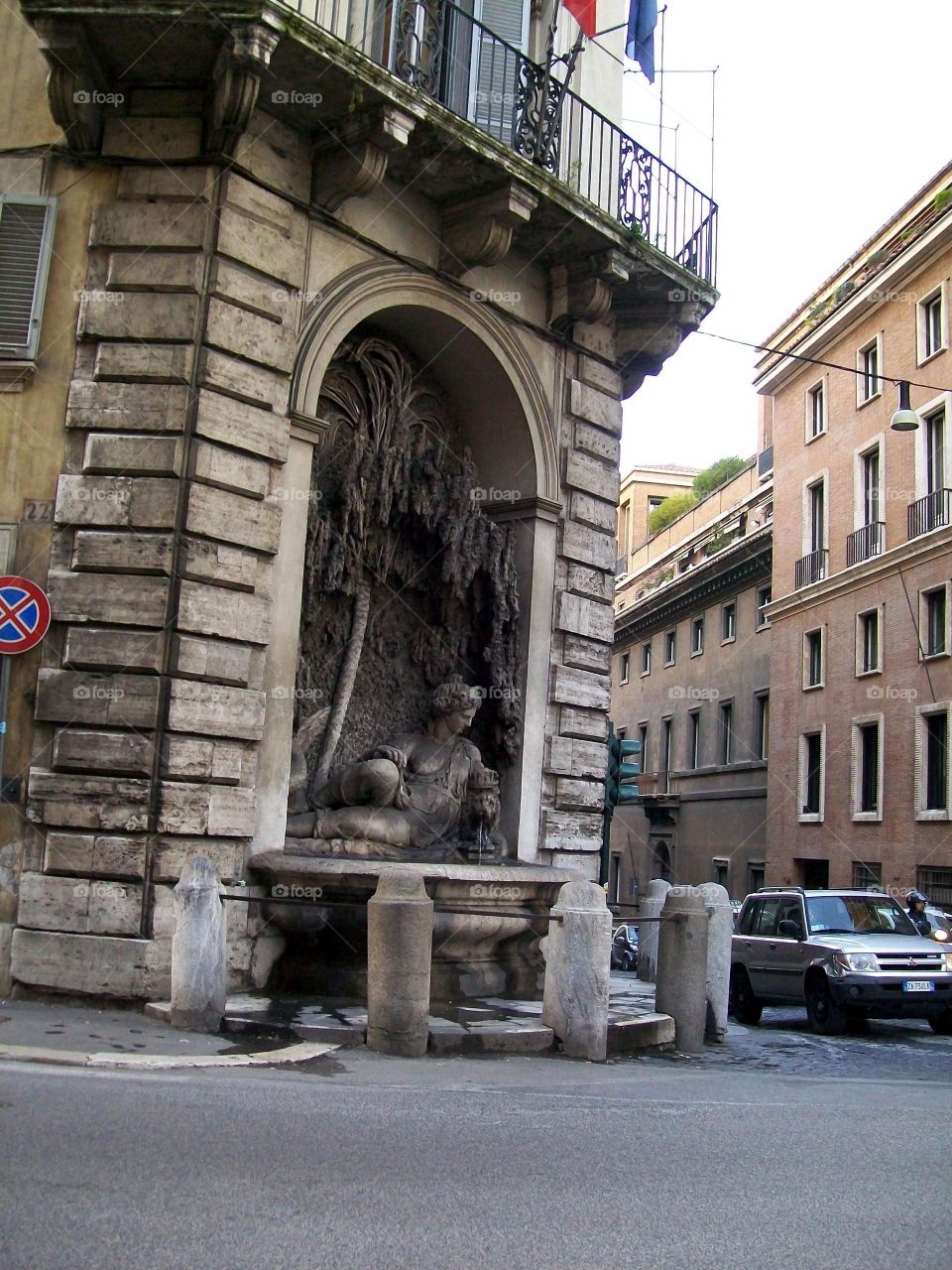 One of the four fountains in Rome with an aged patina and active street traffic beyond