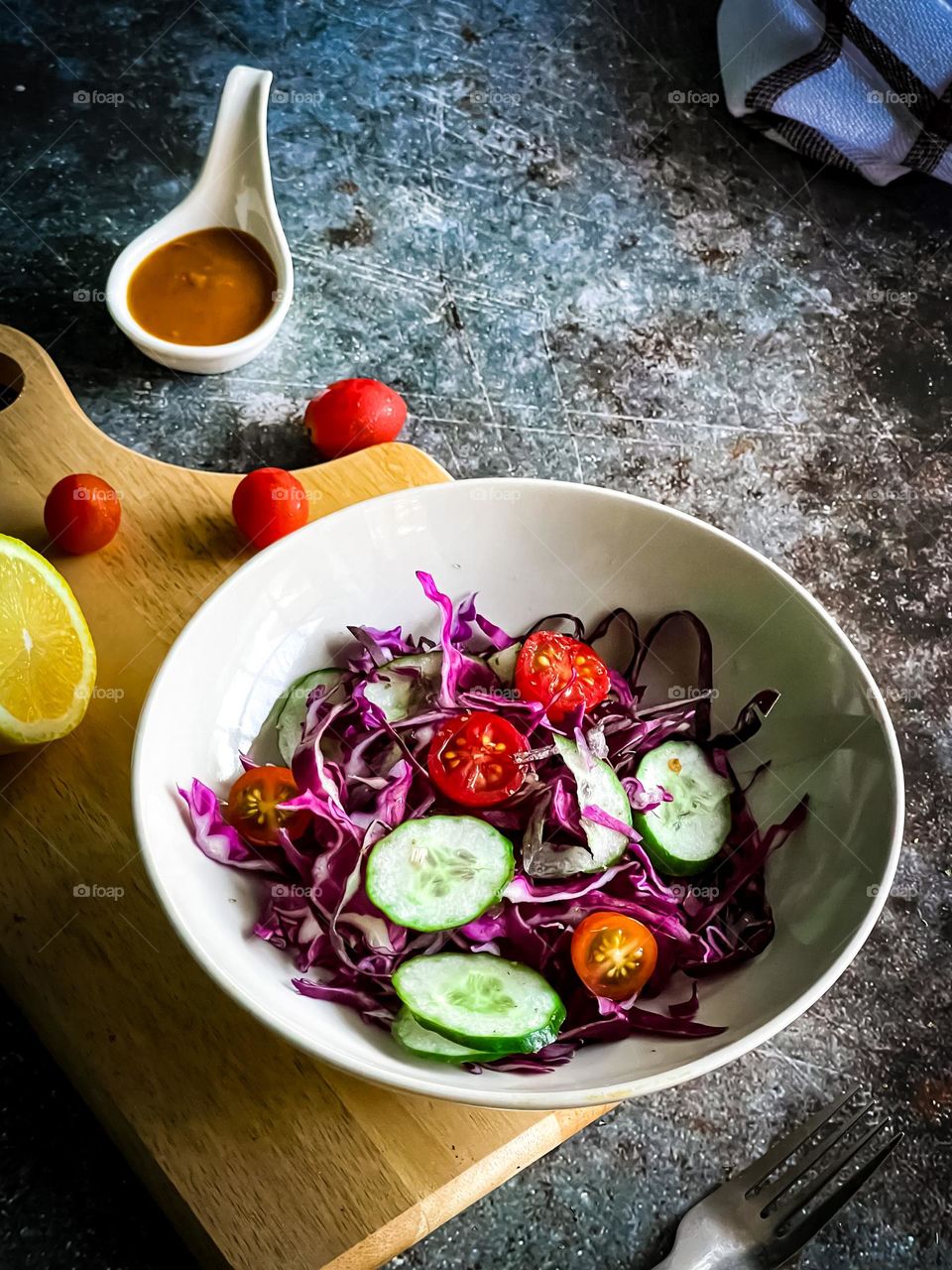 Fresh Rainbow salad in a ceramic bowl on table top with sauce on the side