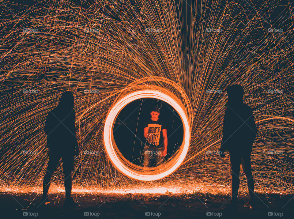 Boy spinning steel wool in front of two silhouettes.
