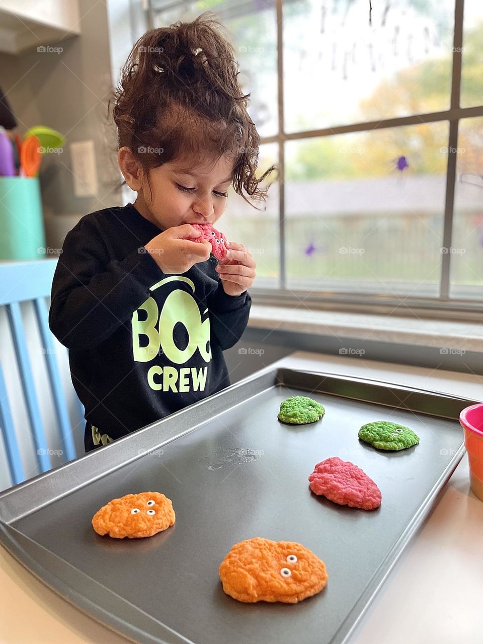 Little girl eats monster cookies from cookie tray, eating Halloween cookies, making cookies with Mommy, homemade cookies, cookie time in the fall, fall treats for Halloween 