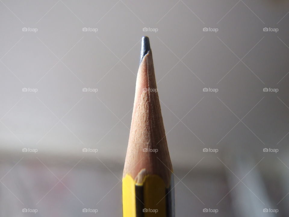 Closeup of tip of a black and yellow pencil with blurry background