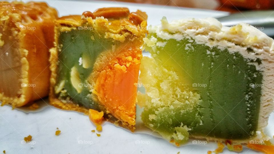 Two different types of pandan flavored mooncakes - one with egg yolk and melon seeds (left), and the other with coconut center (right). Mooncakes are traditionally consumed in celebration of the mid-autumn harvest festival.