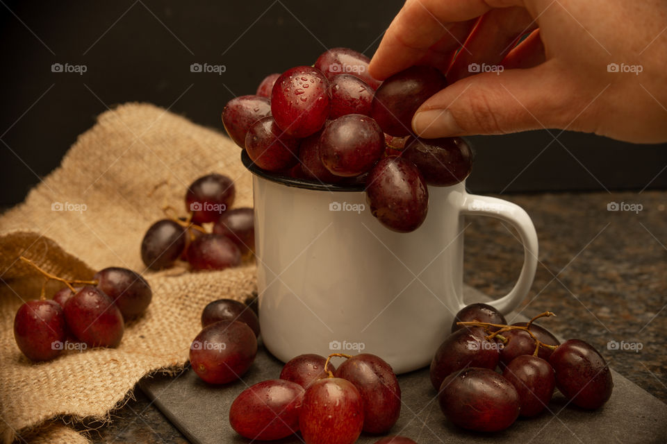 grapes in a cup and a person taking a fruit