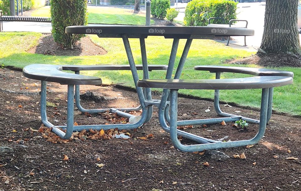 round metal outdoor table with attached bench seating in a green suburban setting in Oregon