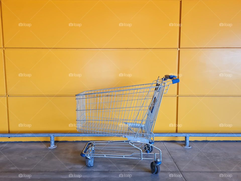 shopping cart in front of a yellow wall