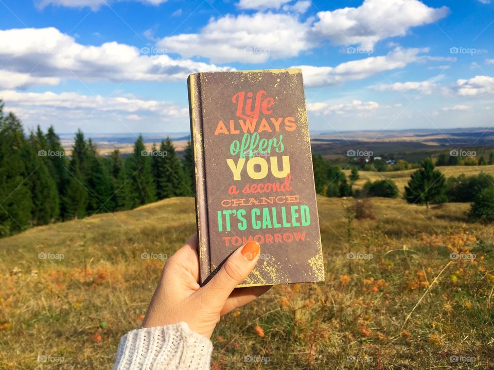 Woman holding a motivational note - life always offers you a second chance, it’s called tomorrow- surrounded by a beautiful landscape in autumn