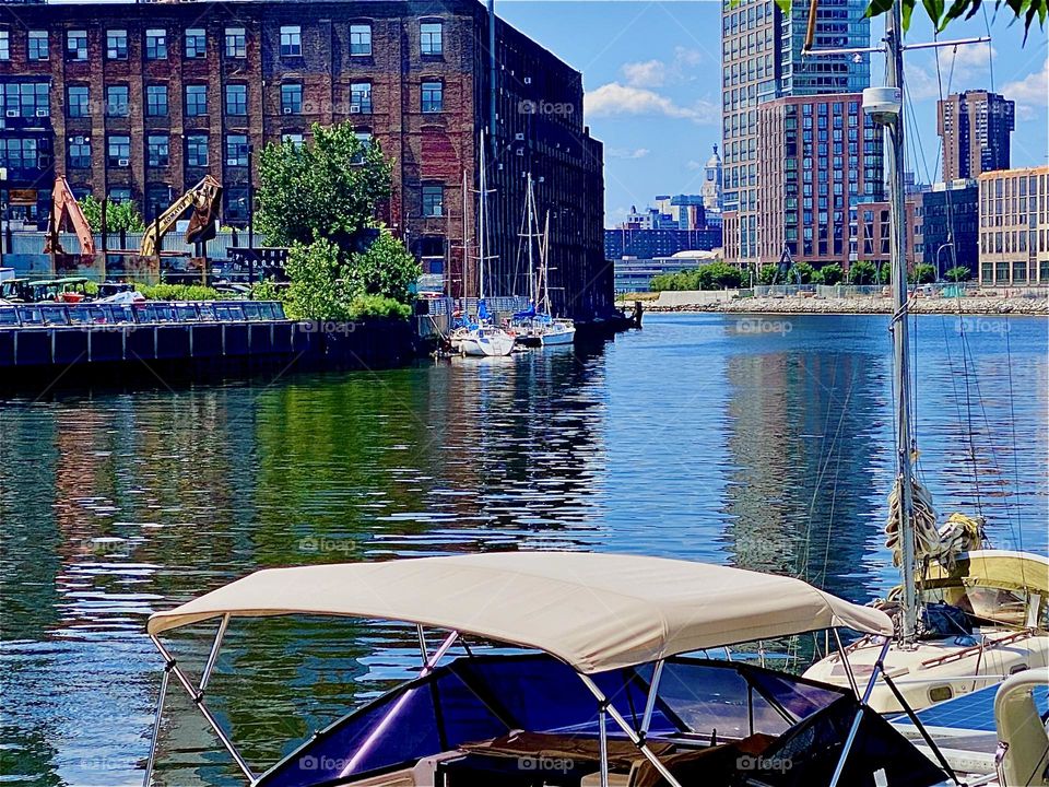 From even closer up the details on the other side of the „East River“ at „Newtown Creek“ in „Greenpoint“, Brooklyn can be distinguished even more such as the sailboats tied up to the dock. 2023. Hypnotic Productions 
