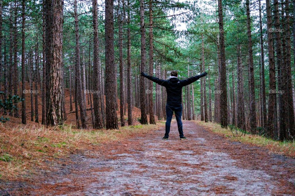 Spending more time in nature! Man spreading his arms between the trees