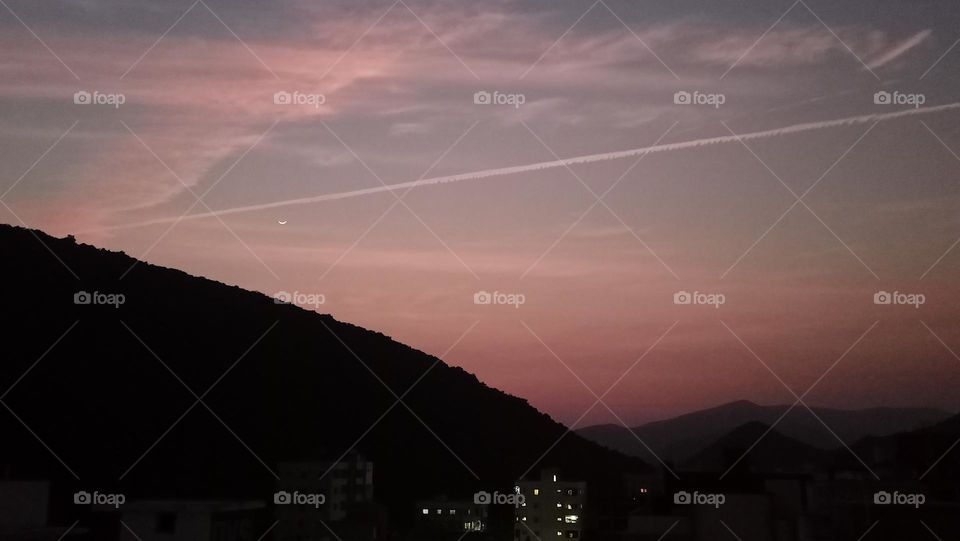 beautiful moon with jet contrail at colourful evening