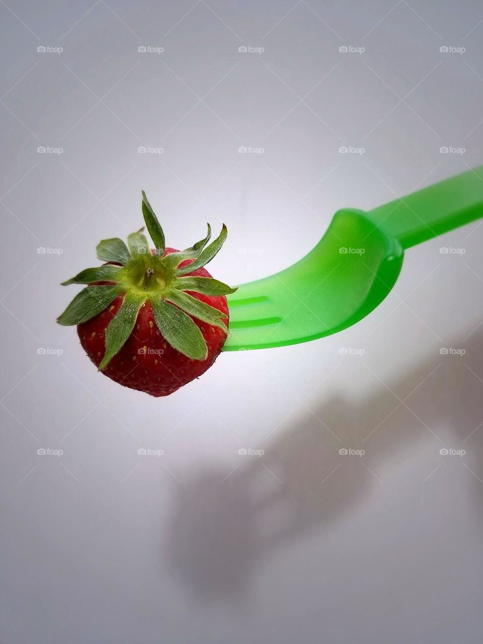 Fork holding Strawberry with shadow