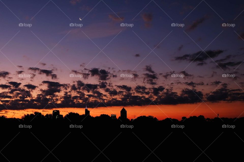 Dark clouds contrast the vivid sky with the moon over Raleigh, North Carolina. 