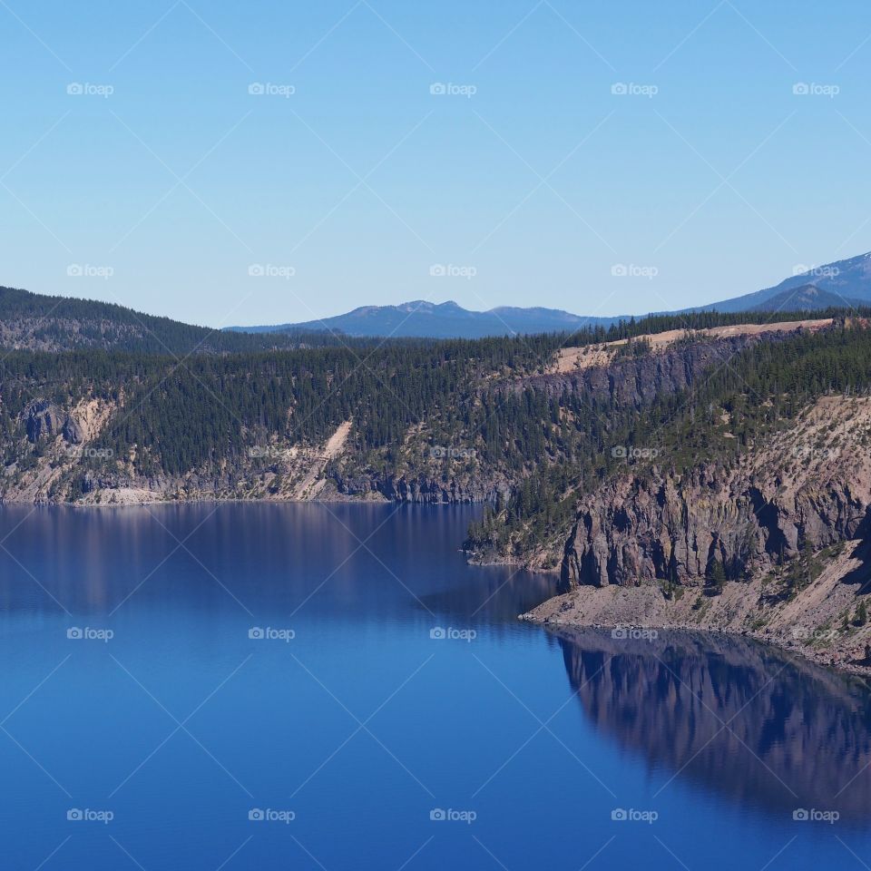 The rugged rim reflecting in the stunning Crater Lake on a beautiful summer morning in Southern Oregon. 