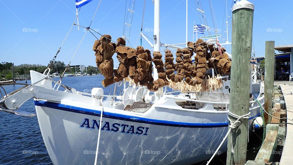 Sponge boat with sponges drying on board sitting at dock in port next to a restaurant 