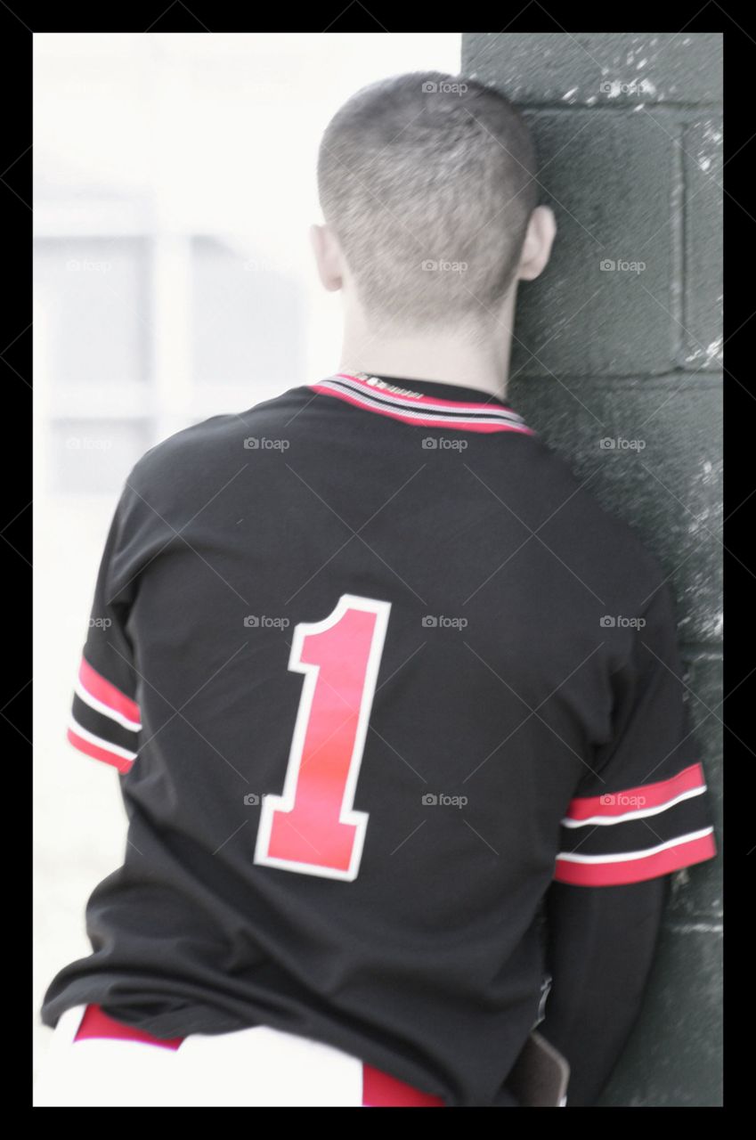 Baseball player leaning against dugout