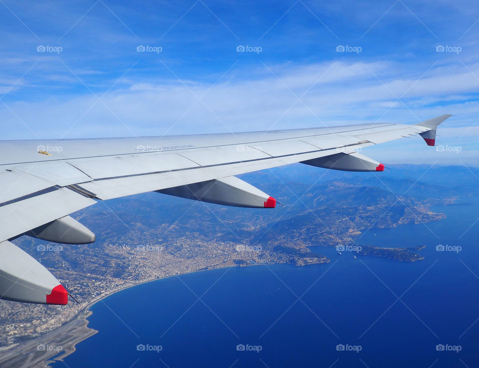 View of the French Riviera from behind wing on airplane flying over Nice, France.