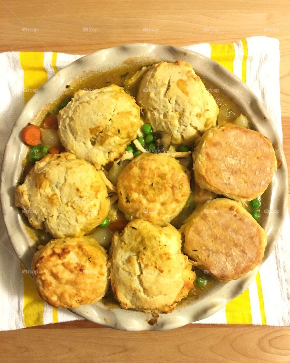 Homemade chicken soup and biscuits on a yellow striped background. 