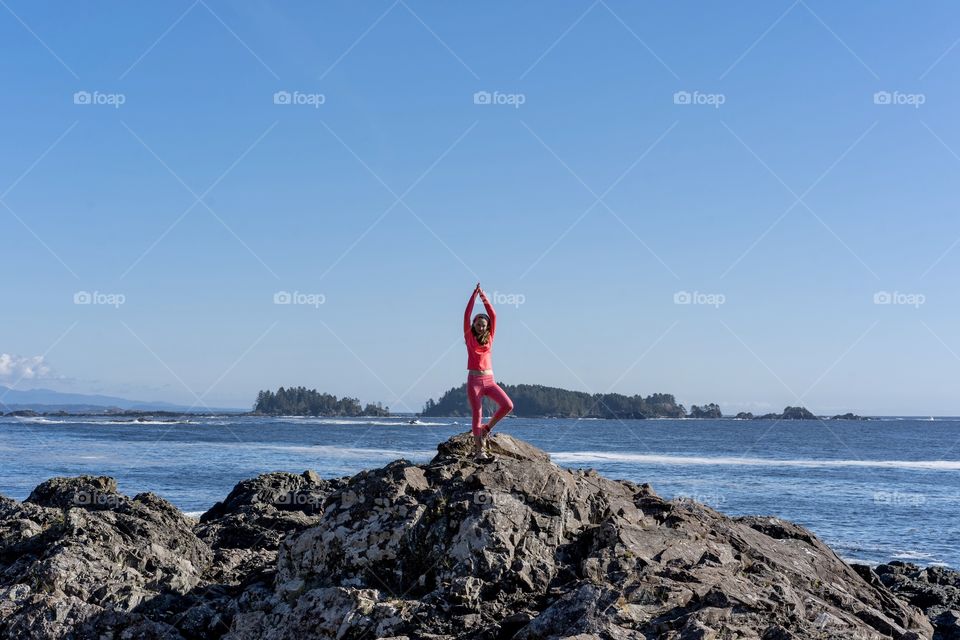 Doing yoga exercises on rocky peak overlooking Pacific Ocean — Ucluelet, British Columbia 