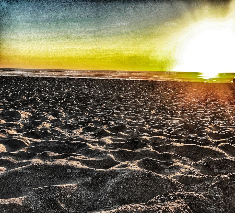 Texturized sand shadowed by the sunset at the ocean