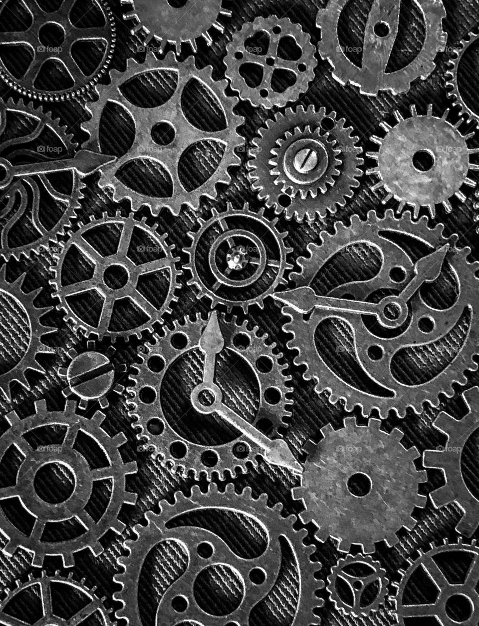 Gunmetal grey cogs, gears and clock hands on a diagonal striped background 