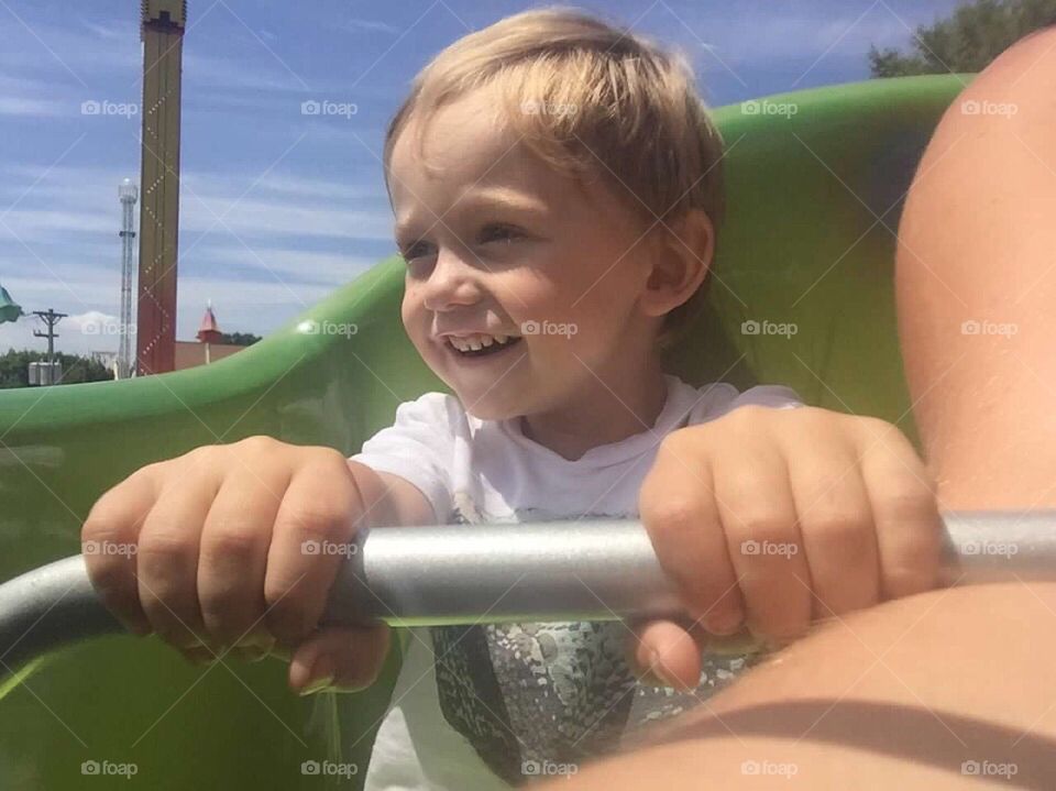 Little boy riding a roller coaster with his mommy. 