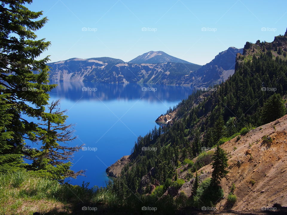 The rugged rim reflecting in the stunning Crater Lake on a beautiful summer morning in Southern Oregon. 