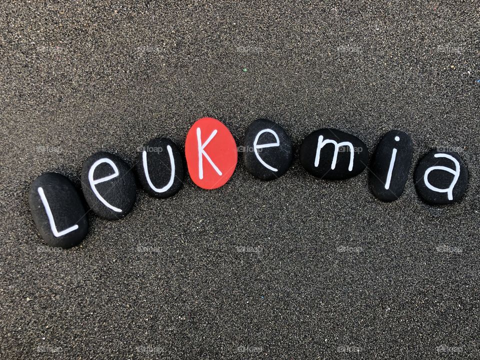 Leukemia, group of cancers text composed with black and red painted stones over black volcanic sand