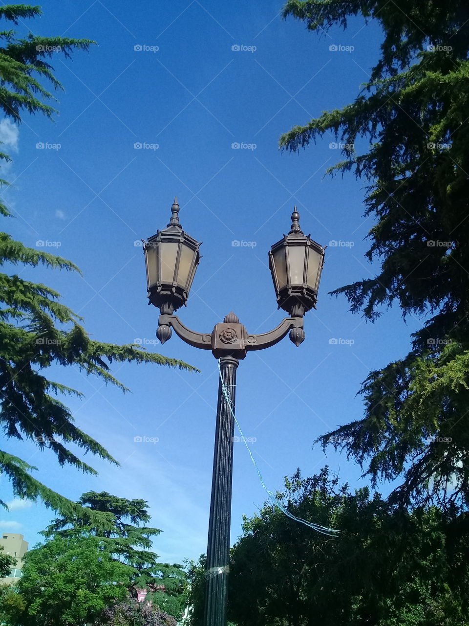 antiguo farol de iluminación de hierro macizo y vidrios originales destacando contra el cielo azul de verano.