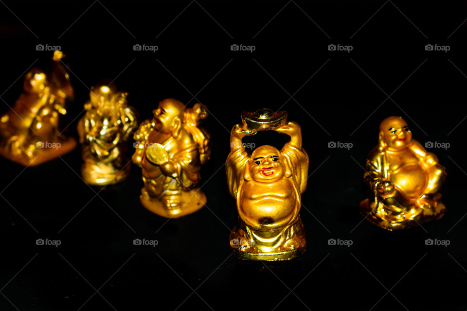A Golden Laughing Buddhas with relaxed mindset. Isolated in a dark background. Selective focus and shallow depth of field