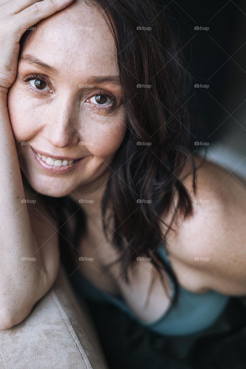 Adult brunette self loving forty years woman with natural skin with freckles and wrinkles at home 