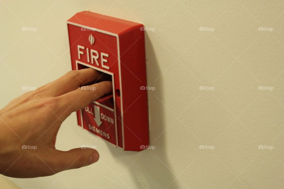 Emergency Situation hand pulling fire alarm on wall
