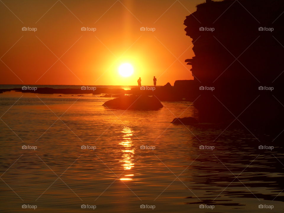 people on a orange sunset sea shore summer time