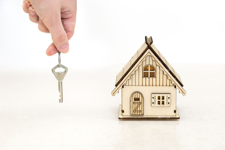 toy house and key in hand on a white background