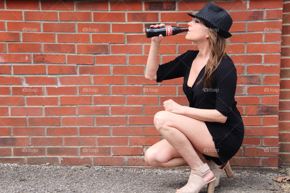 Female in front of brick wall holding Coca Cola 