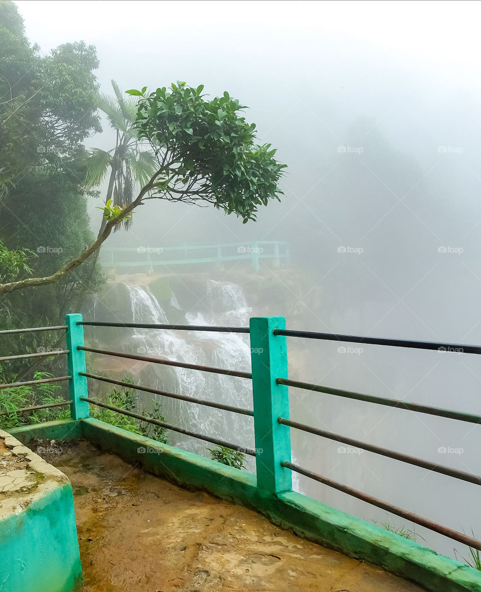 small waterfall amidst forest with lots of fog or mist creating winter like weather