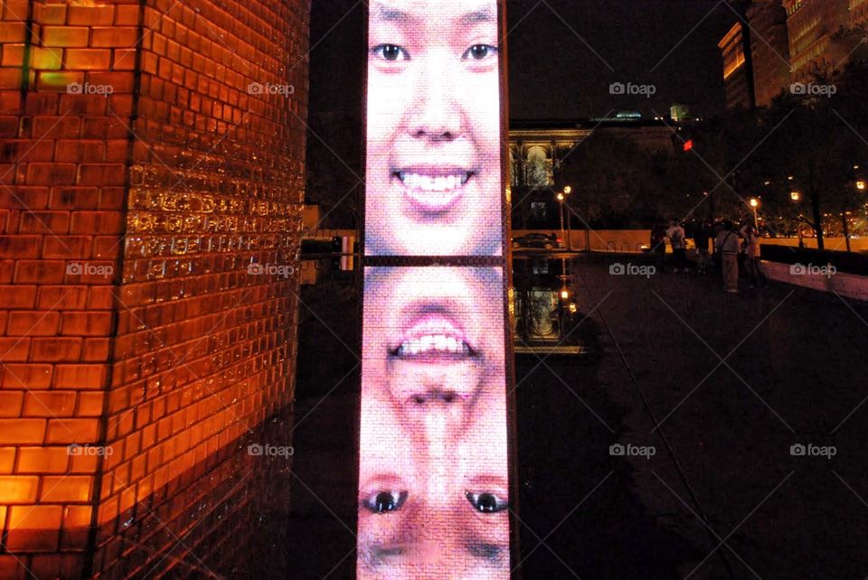 Faces on a Chicago night. Light tower with giant projected faces reflected  at night at millennium Park in Chicago