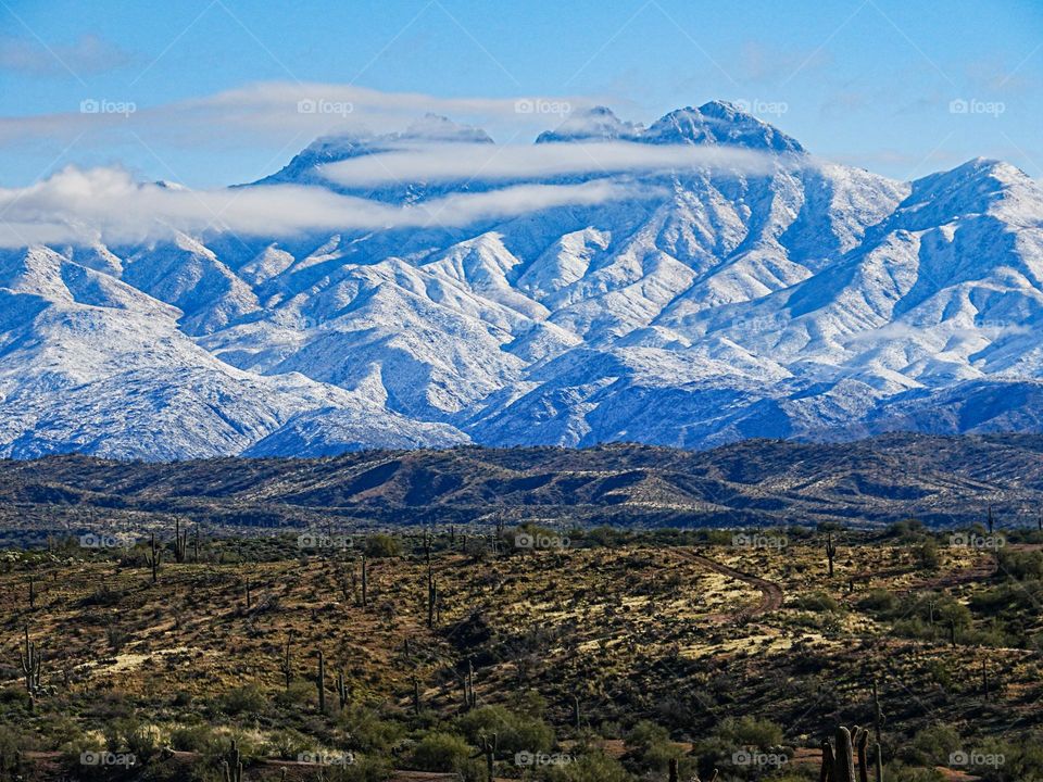 Clouds drift in front of the Four Peaks mountains after a recent snow storm left them snow capped