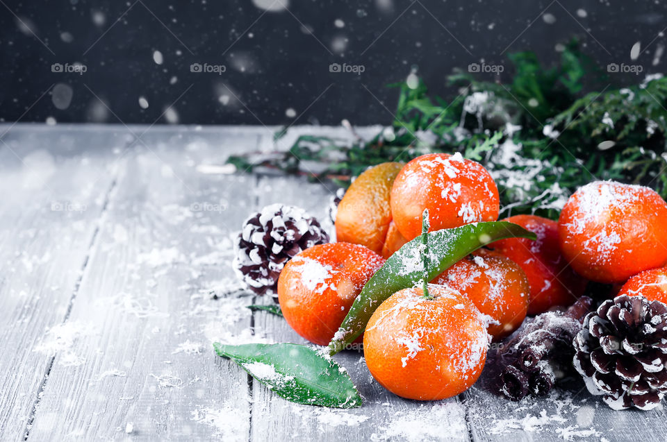 tangerines with snow on a dark wooden background