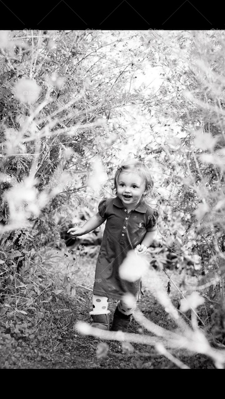 Little girl running through the wild flower patch in black and white