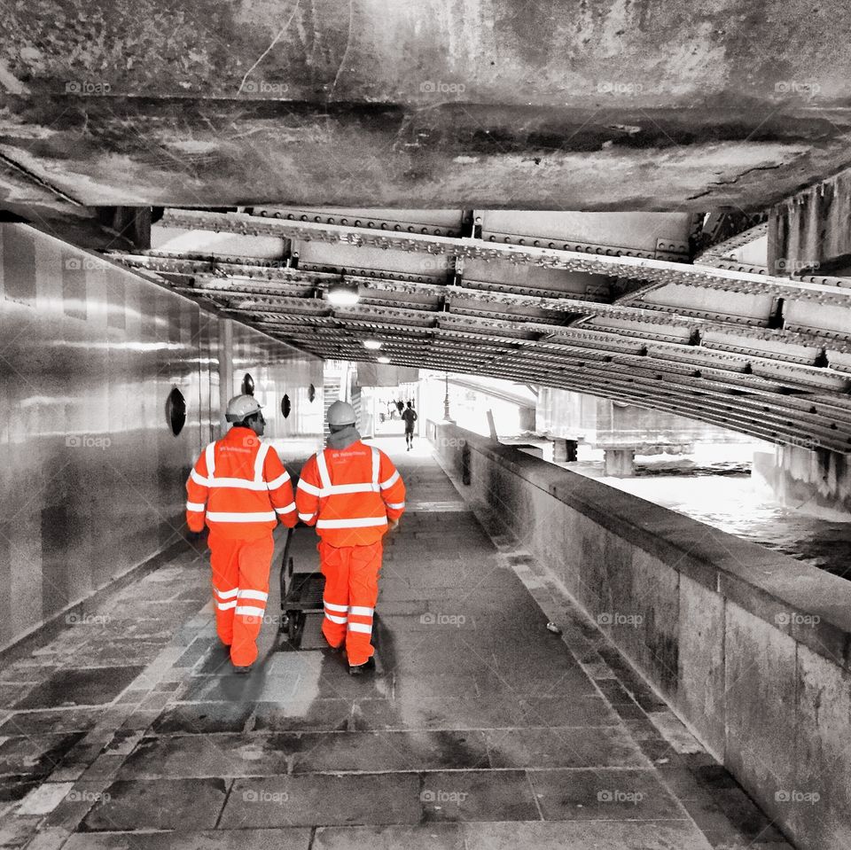 Workmen walking under a bridge in London 