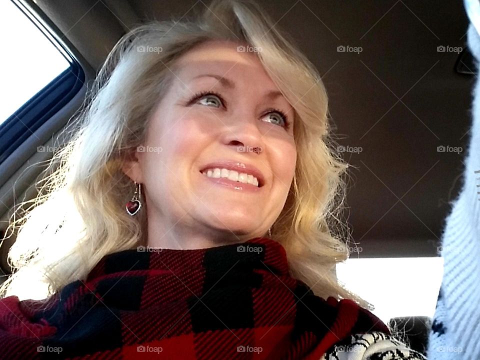 Woman wearing eyeshadow sitting in a car smiling