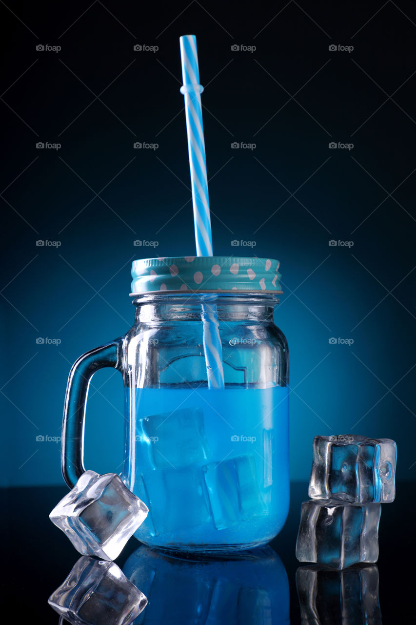 Blue cocktail in a mason jar on blue background