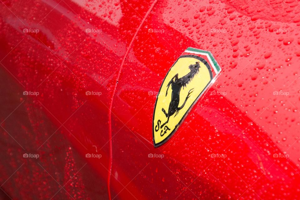 A blood red Ferrari coverd in rain drops