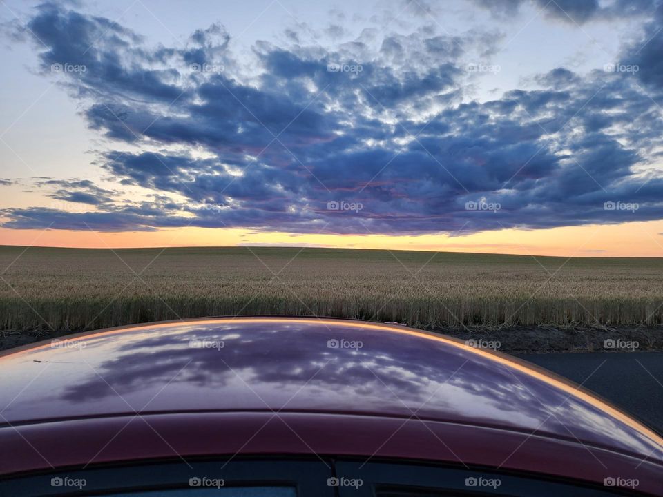 stunning dark clouds and orange sky sunset reflecting on car roof on an Oregon  Summer evening drive