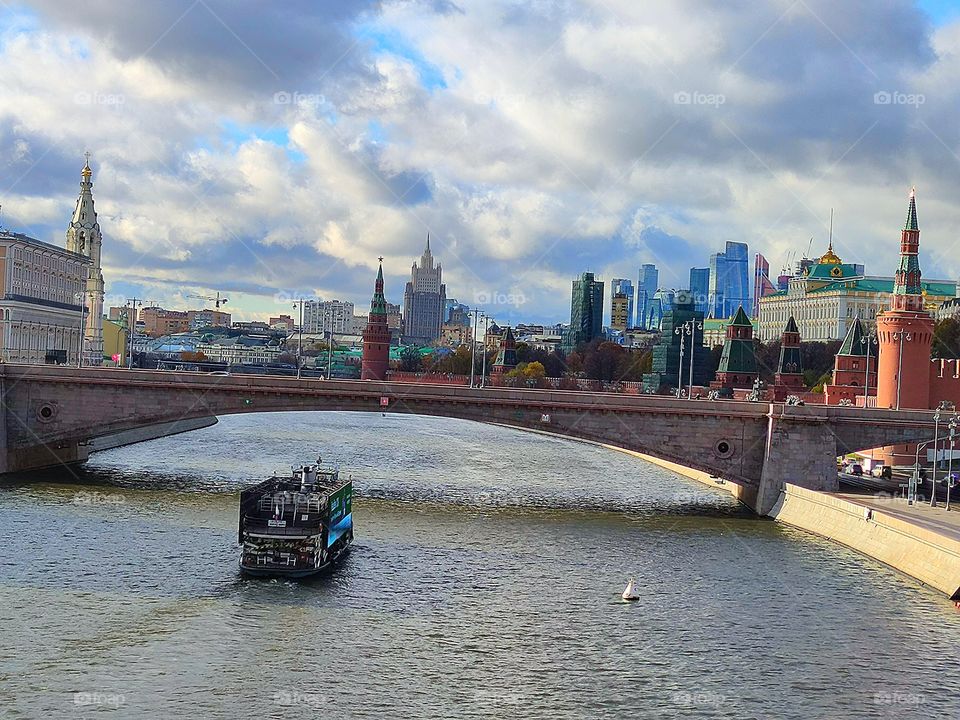 Moscow.  View from the "floating bridge".  Moskva River, Bolshoi Zamoskvoretsky Bridge, Moskvoretskaya Embankment with cars.  A pleasure steamer is sailing along the river.  In the background: Moscow Kremlin, Moscow City, Russian Foreign Ministry