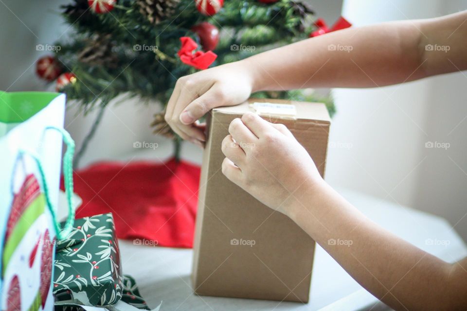 Child's hands are unwrapping her Christmas present