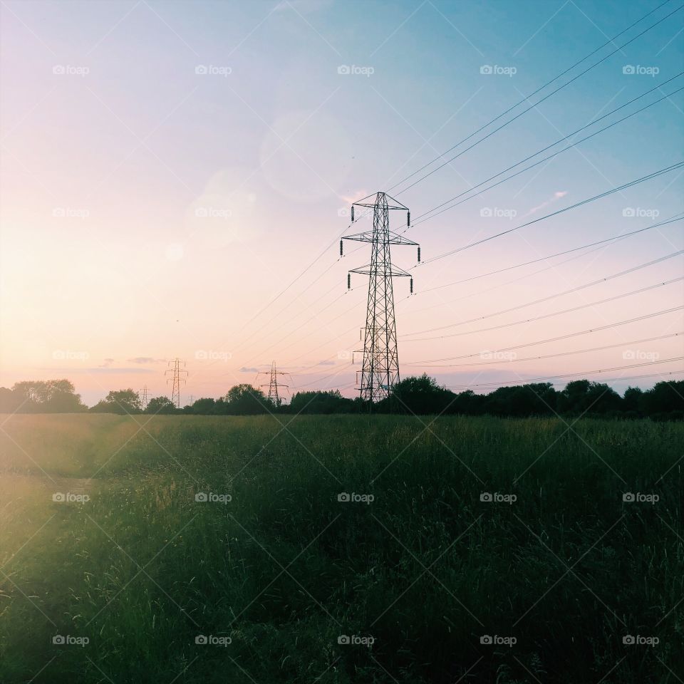 Power line in field during sunset, colourful sky 