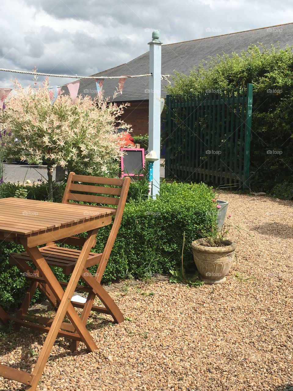 Tea garden landscape featuring table and chair against a pink flamingo Salix tree and bunting