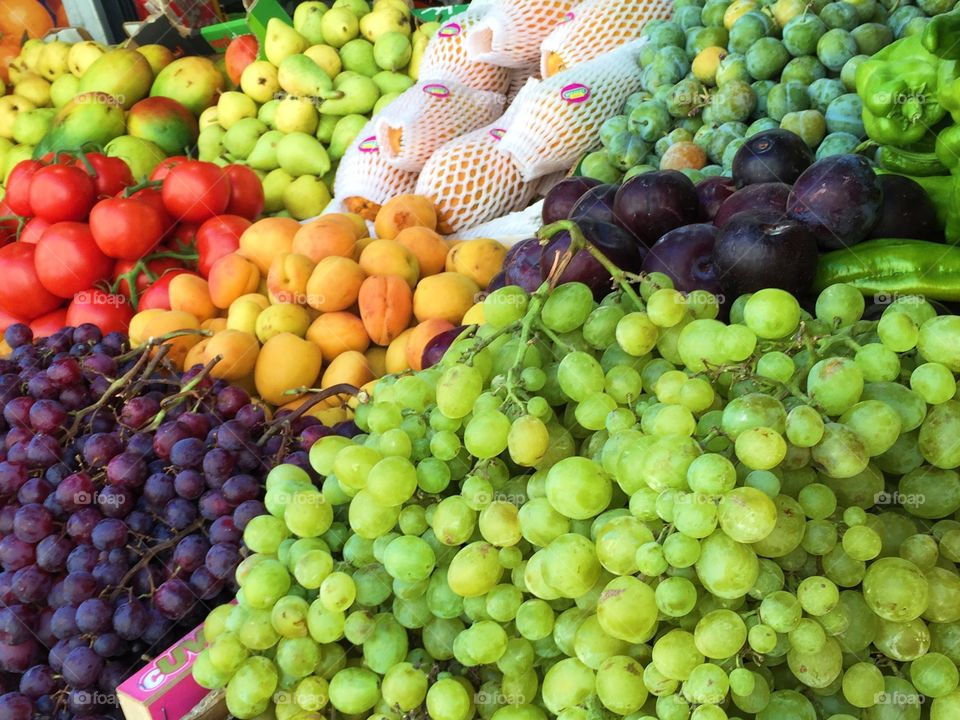 Green and black grapes, plums and other fresh fruits on a market stall 