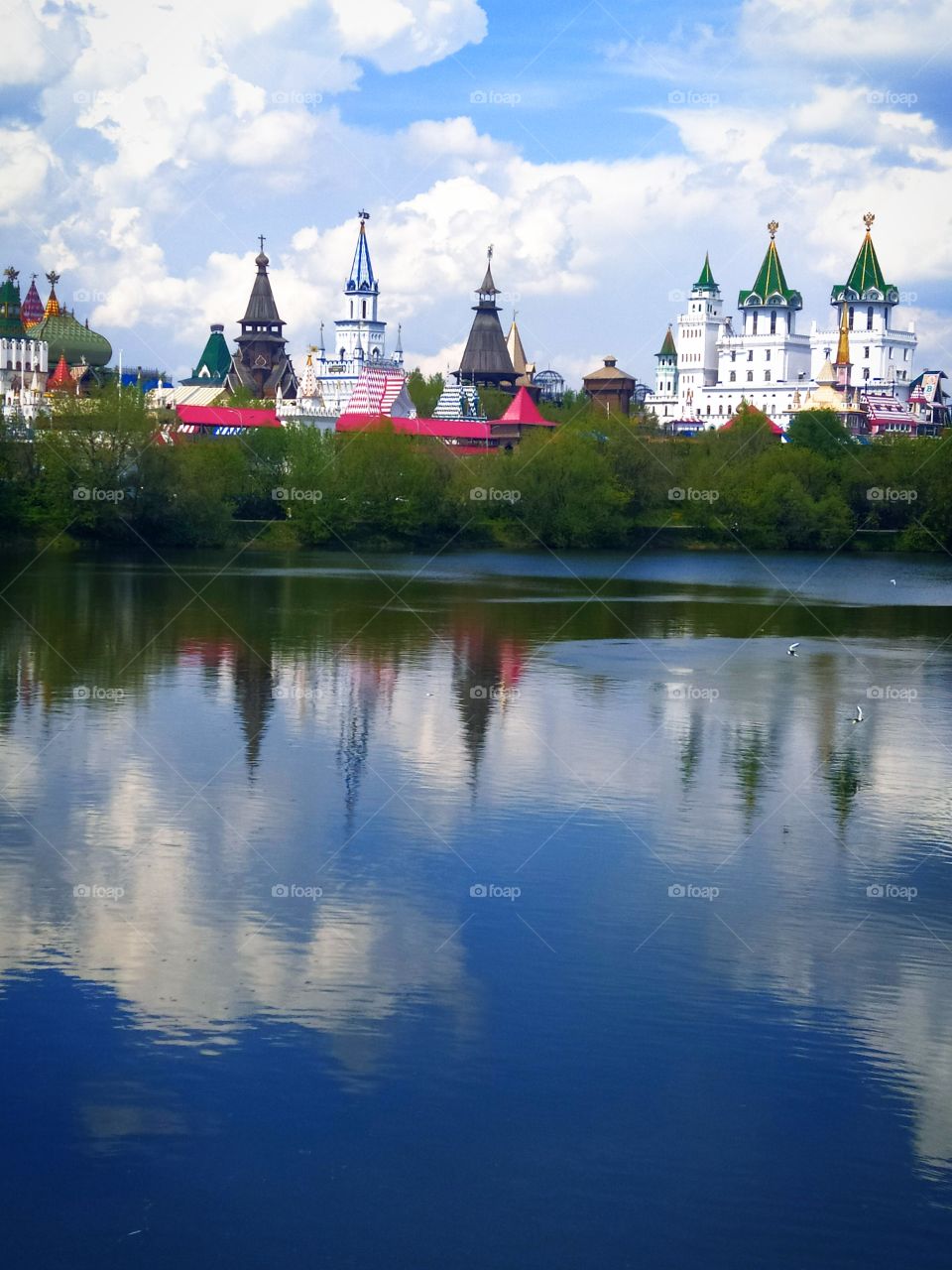 River in the morning.  Reflection in the water of the blue sky, white clouds and towers