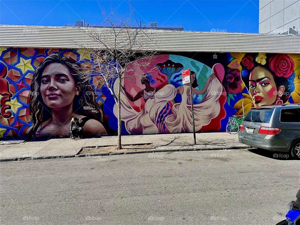 This is a gorgeous art mural on „Jefferson Street“ off „Broadway“ in „Bushwick“, Brooklyn showing a young Hispanic lady next to the word „PRIDE“, two dark skinned Latin dancers in flowing white dresses and a mulatto lady. 2024. Hypnotic Productions